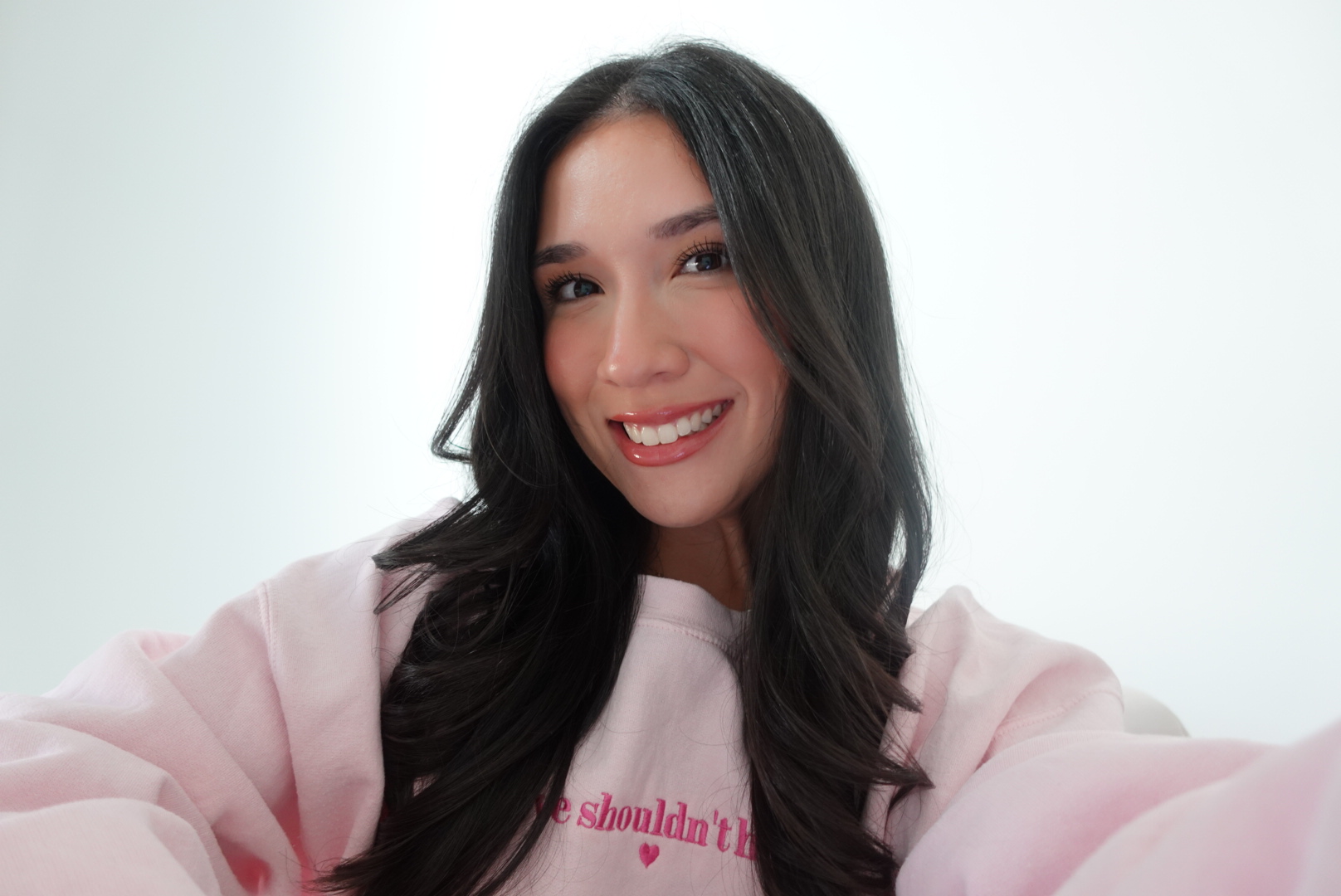 Christy, founder of MNY The Movement, smiling in a pink hoodie